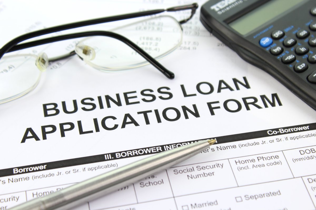 Business loan application form with calculator, pen, and glasses – cover image for Bad Credit (Georg Rockall-Schmidt interview)